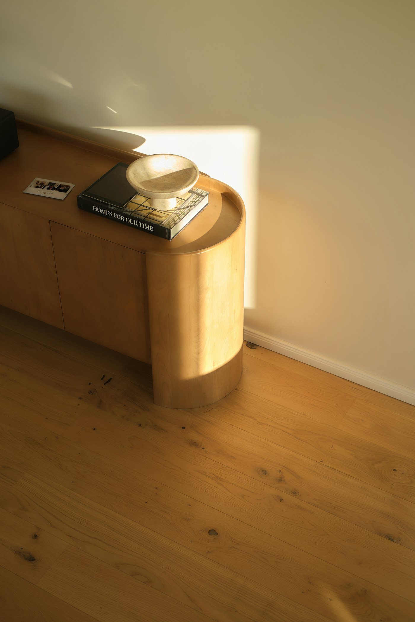 Meuble aux portes cintrées en bois clair baigné de lumière
